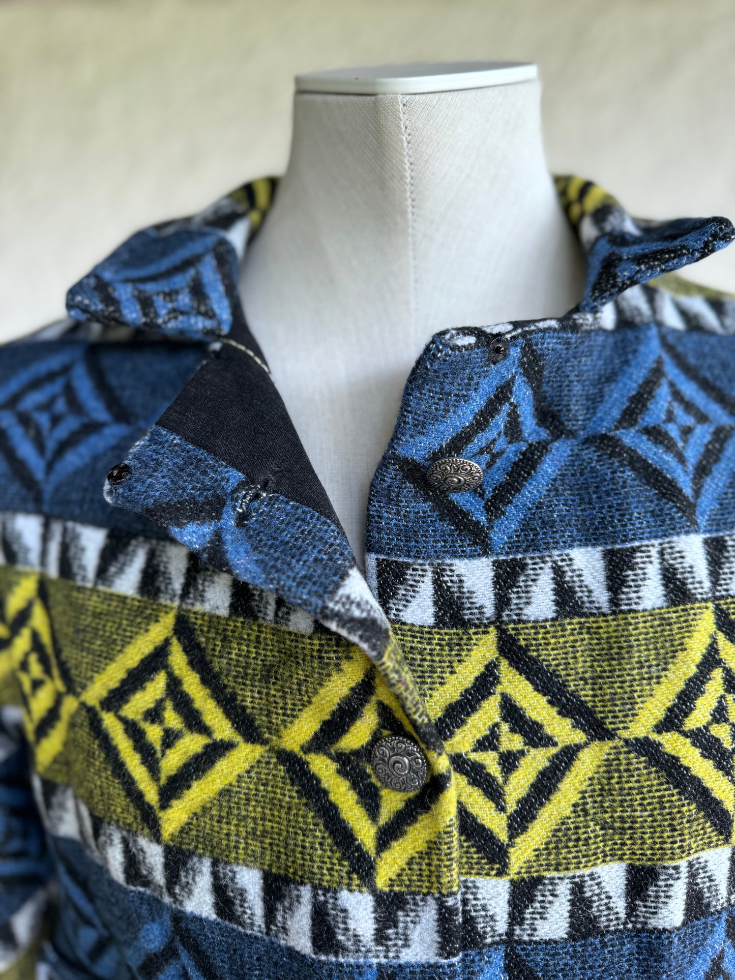 close up of the collar and button closure of the blue and yellow one of a kind short jacket, boxy fit with two square pockets, silver tone metal buttons